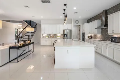 a kitchen with stainless steel appliances kitchen island a table chairs sink and cabinets