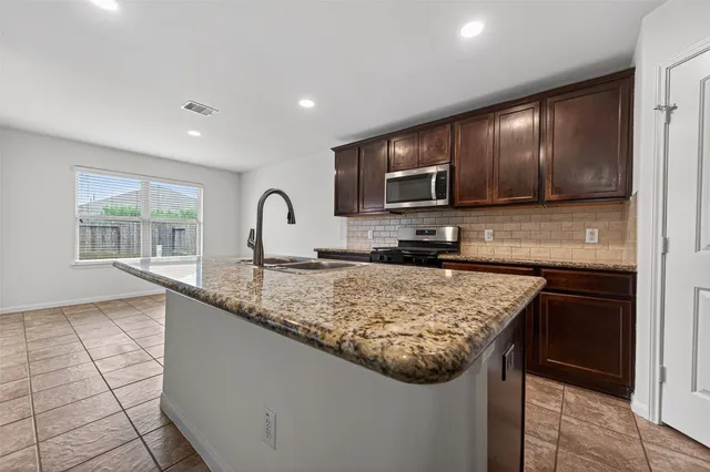 a kitchen with kitchen island granite countertop a sink stove and refrigerator