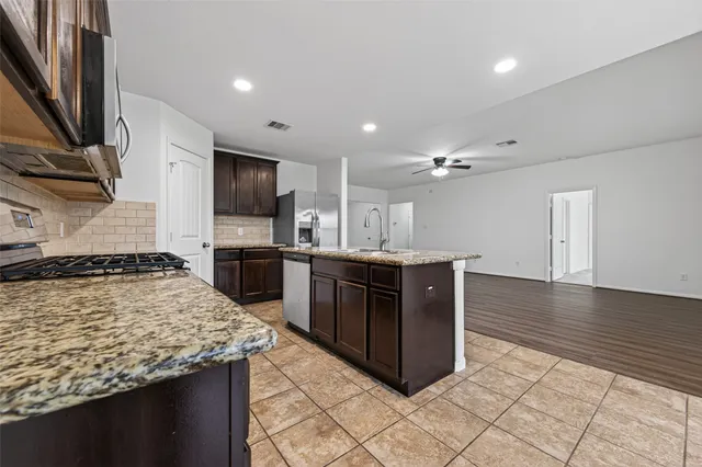 a kitchen with stainless steel appliances granite countertop a stove a sink and a refrigerator