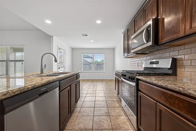 a kitchen with granite countertop stainless steel appliances and a sink