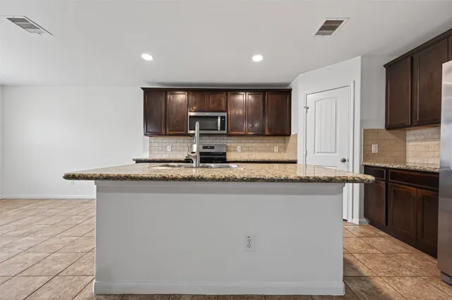 a kitchen with kitchen island granite countertop a sink stove and refrigerator