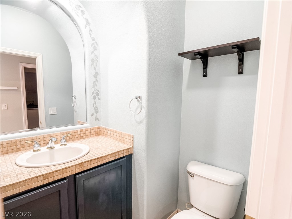 8683 Moreno Mountain Avenue Las Vegas, NV 89178 - Photo 10 of 26 A compact half-bath features an arched mirror and mosaic-tiled vanity.
