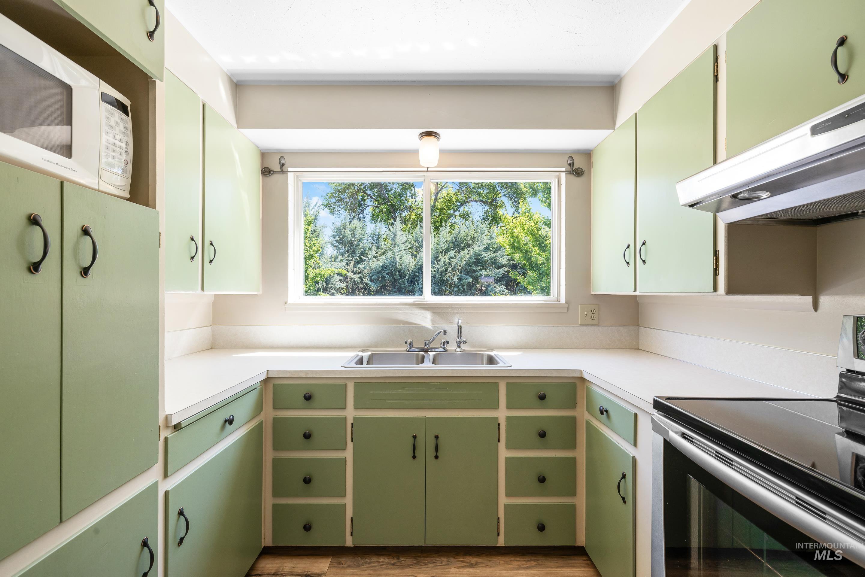 708 South Phillippi Street Boise, ID 83705 - Photo 9 of 25 Kitchen featuring light green cabinetry with dark hardware, white countertops, and wood-finish flooring