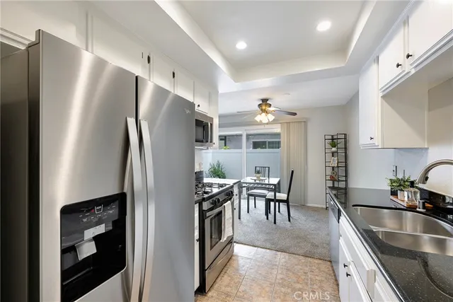 a kitchen with stainless steel appliances granite countertop a sink a stove and white cabinets