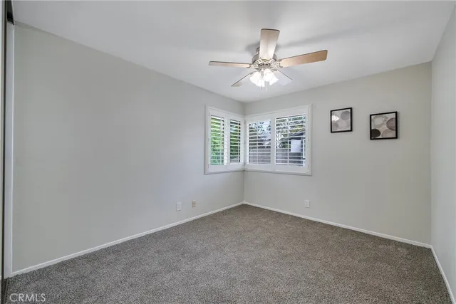 an empty room with a chandelier fan and a window