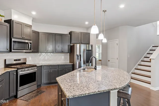 a kitchen with stainless steel appliances granite countertop a sink dishwasher a refrigerator and a stove with wooden floor