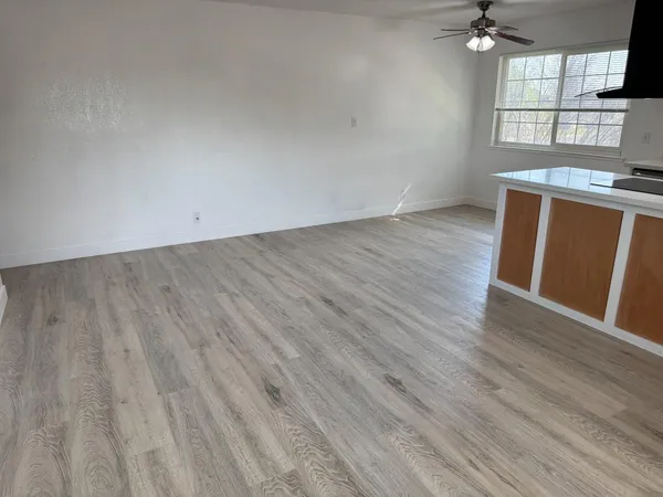 an empty room with wooden floor and windows