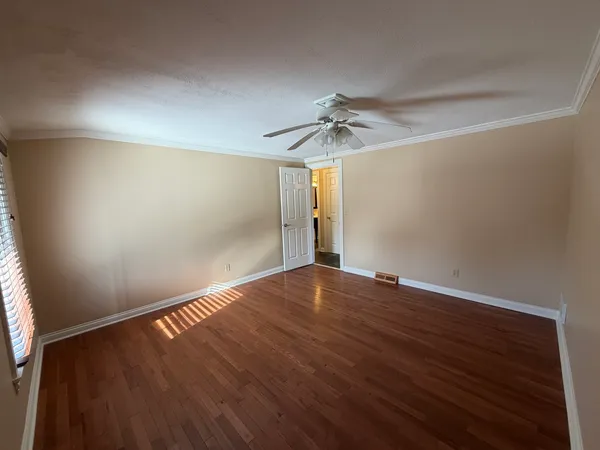 a view of empty room with wooden floor and fan