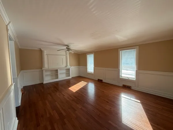an empty room with wooden floor and windows