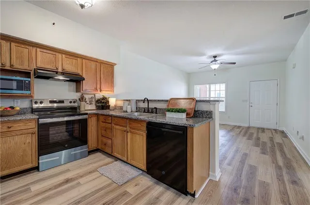 a kitchen with granite countertop a sink cabinets and stainless steel appliances