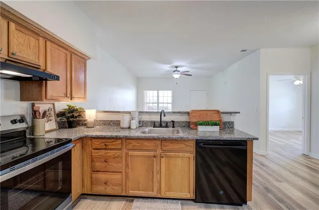 a kitchen with granite countertop a sink cabinets and stainless steel appliances