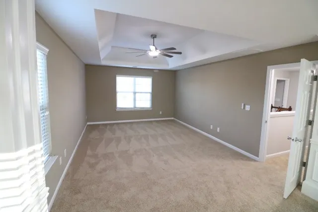 an empty room with windows and ceiling fan