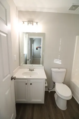 a white toilet sitting next to a bathroom sink and vanity