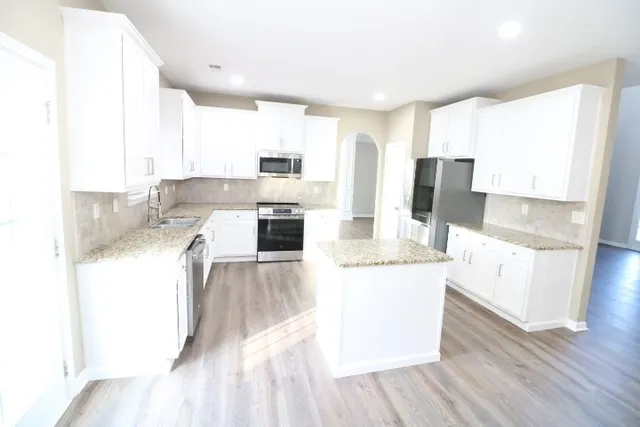 a kitchen with stainless steel appliances granite countertop a refrigerator a stove and a wooden floors