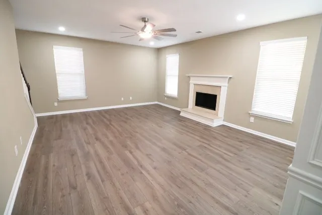 an empty room with wooden floor fireplace and windows