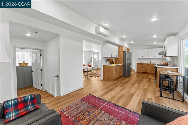 a living room with stainless steel appliances furniture and a wooden floor