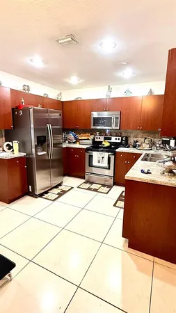 a kitchen with stainless steel appliances kitchen island granite countertop a sink stove and refrigerator