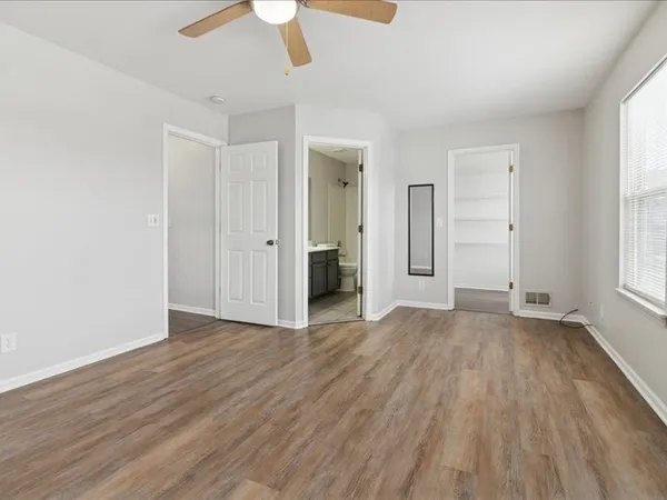 an empty room with wooden floor cabinet and windows