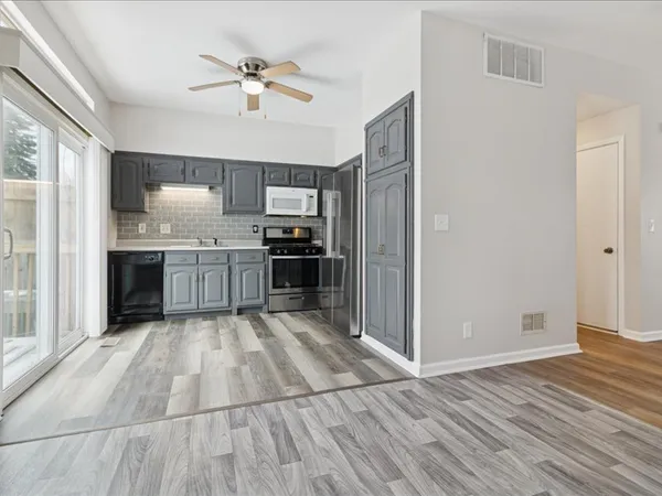 a large kitchen with wooden floor and stainless steel appliances
