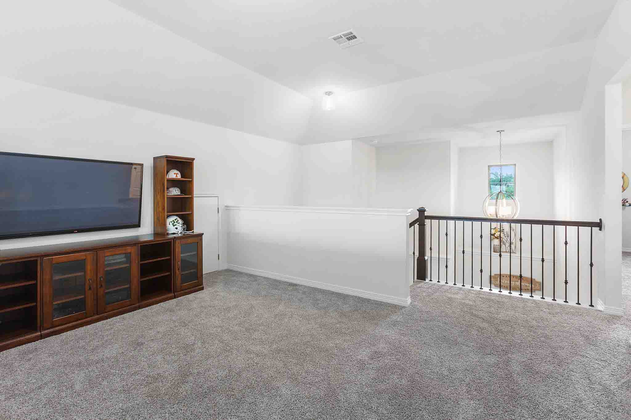 166 West Branch Road Kyle, TX 78640 - Photo 23 of 39 A well-lit loft space features soft carpeting and a wrought iron staircase.