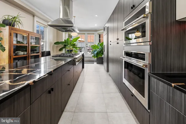 a large kitchen with stainless steel appliances a large counter top a stove and a refrigerator