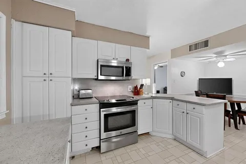 a kitchen with white cabinets and appliances