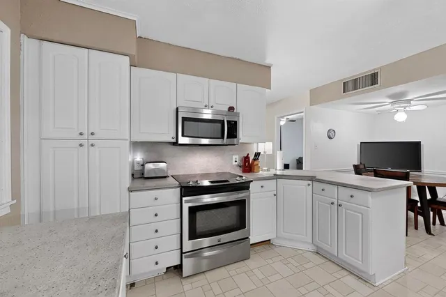 a kitchen with white cabinets and appliances