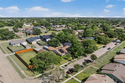 an aerial view of residential houses with outdoor space and trees