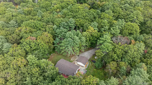 an aerial view of a house with a yard and trees all around