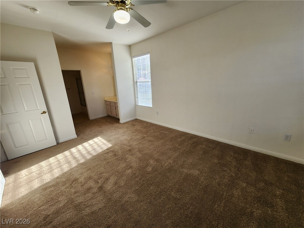 231 West Horizon Ridge Parkway, Unit 417 Henderson, NV 89012 - Photo 32 of 45 Unfurnished bedroom featuring dark carpet, a ceiling fan, and ensuite bathroom