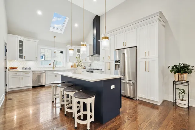 a kitchen with stainless steel appliances a sink a stove a refrigerator and island with wooden floor