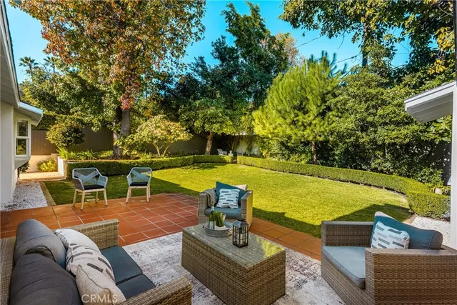 a view of a patio with couches potted plants and a large tree