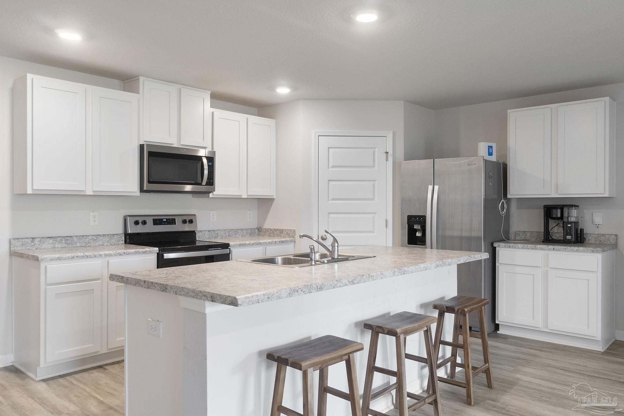 4358 Redbay Court Pace, FL 32571 - Photo 11 of 47 a kitchen with stainless steel appliances granite countertop a stove a sink a microwave a refrigerator and white cabinets with wooden floor