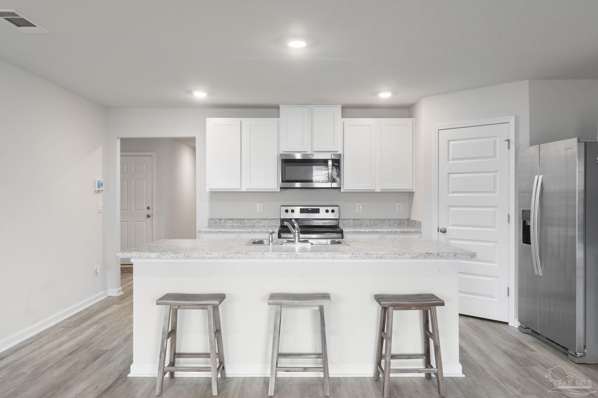 4358 Redbay Court Pace, FL 32571 - Photo 12 of 47 a kitchen with stainless steel appliances granite countertop a white cabinets and a refrigerator