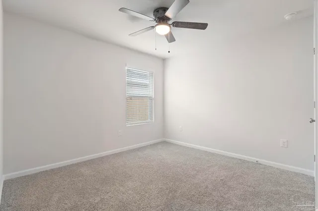 an empty room with a window and a fan