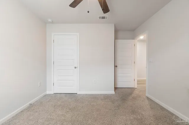 an empty room with closet and a ceiling fan