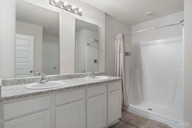 a bathroom with a granite countertop sink a mirror and a shower