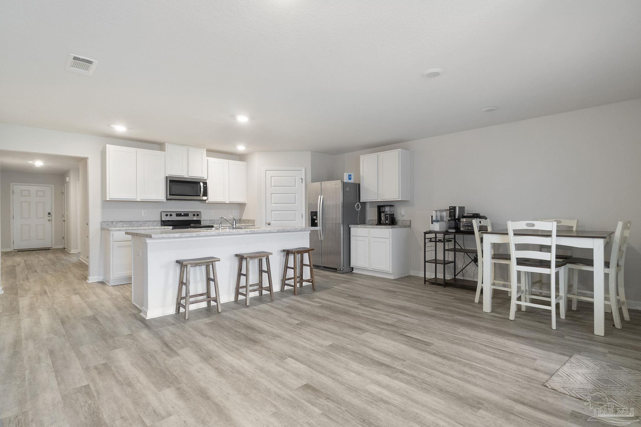 4358 Redbay Court Pace, FL 32571 - Photo 10 of 47 a kitchen with white cabinets and stainless steel appliances