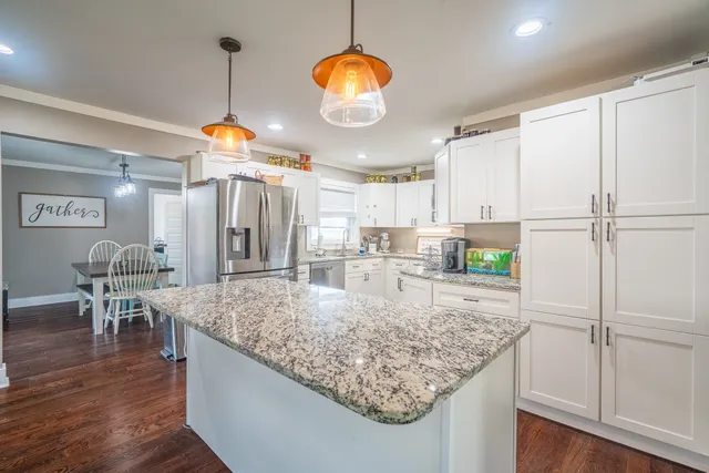 a kitchen with stainless steel appliances granite countertop a sink refrigerator and cabinets