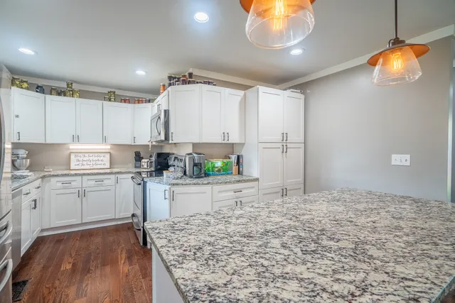 a kitchen with white cabinets and wooden floor