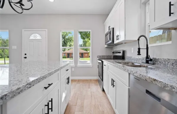 a kitchen with granite countertop a sink stove and cabinets