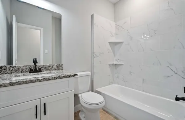 a bathroom with a granite countertop sink a toilet and a bathtub