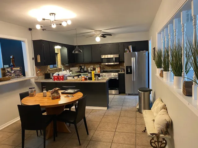 a kitchen with stainless steel appliances kitchen island granite countertop a sink dishwasher and cabinets with wooden floor