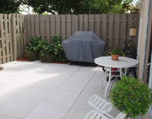 22250 Boca Rancho Drive, Unit D Boca Raton, FL 33428 - Photo 4 of 5 a view of a backyard with table and chairs potted plants and wooden fence