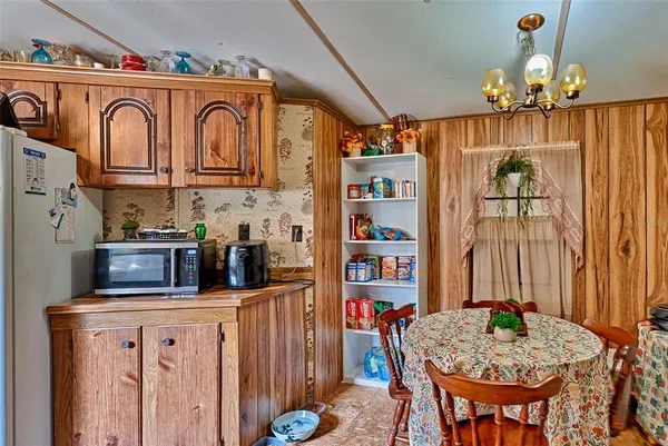 a kitchen with stainless steel appliances granite countertop a dining table chairs and chandelier