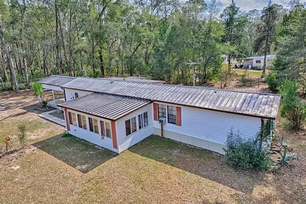 a view of a house with a yard plants and large tree