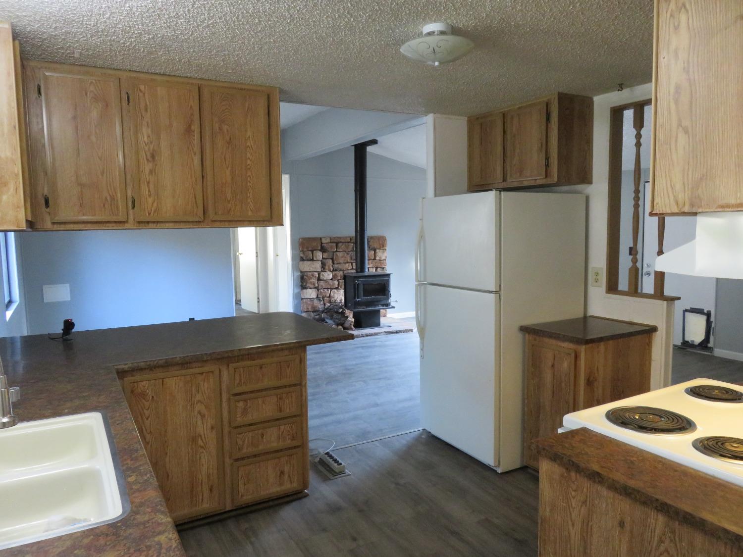 4426 Bald Mountain Road West Point, CA 95255 - Photo 27 of 45 a kitchen with granite countertop wooden cabinets and a refrigerator