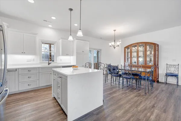a open kitchen with a dining table chairs refrigerator and cabinets
