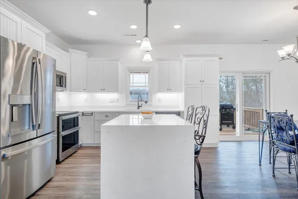 a kitchen with stainless steel appliances a refrigerator a stove a sink a dining table and chairs