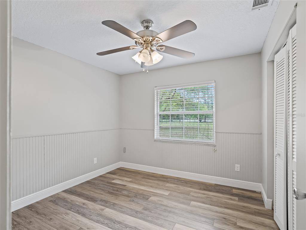 8234 Highway 301 Bushnell, FL 33513 - Photo 23 of 52 an empty room with wooden floor fan and windows